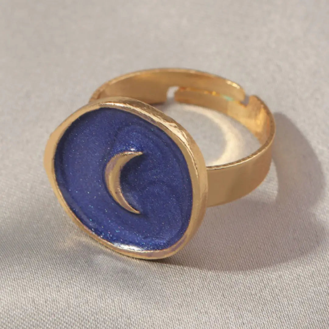 Gold ring with a blue stone and crescent moon design on a light gray background